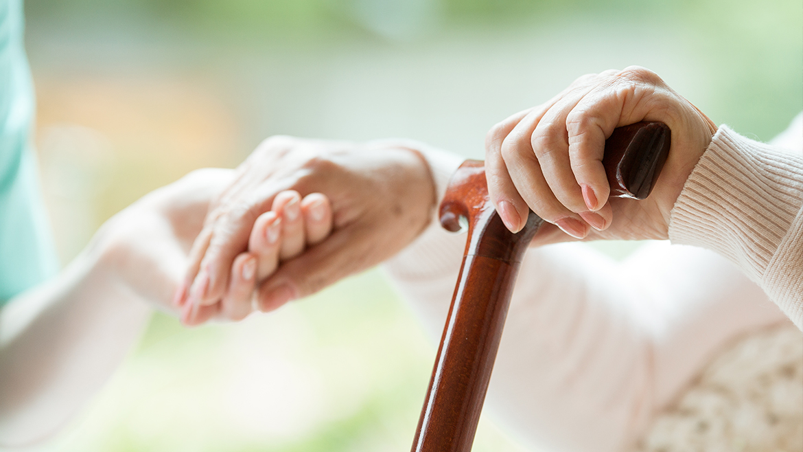 Una persona stringe la mano a una persona anziana con bastone da passeggio